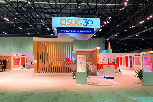 Photos of ASUG booth at SAP Sapphire featuring large overhead sign with 30th anniversary logo and wood slat wall around seating area.