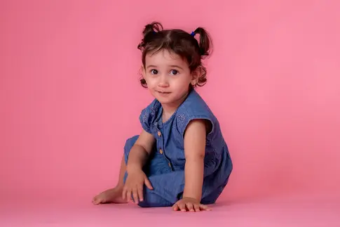 menina em sessão fotográfica infantil com fundo rosa