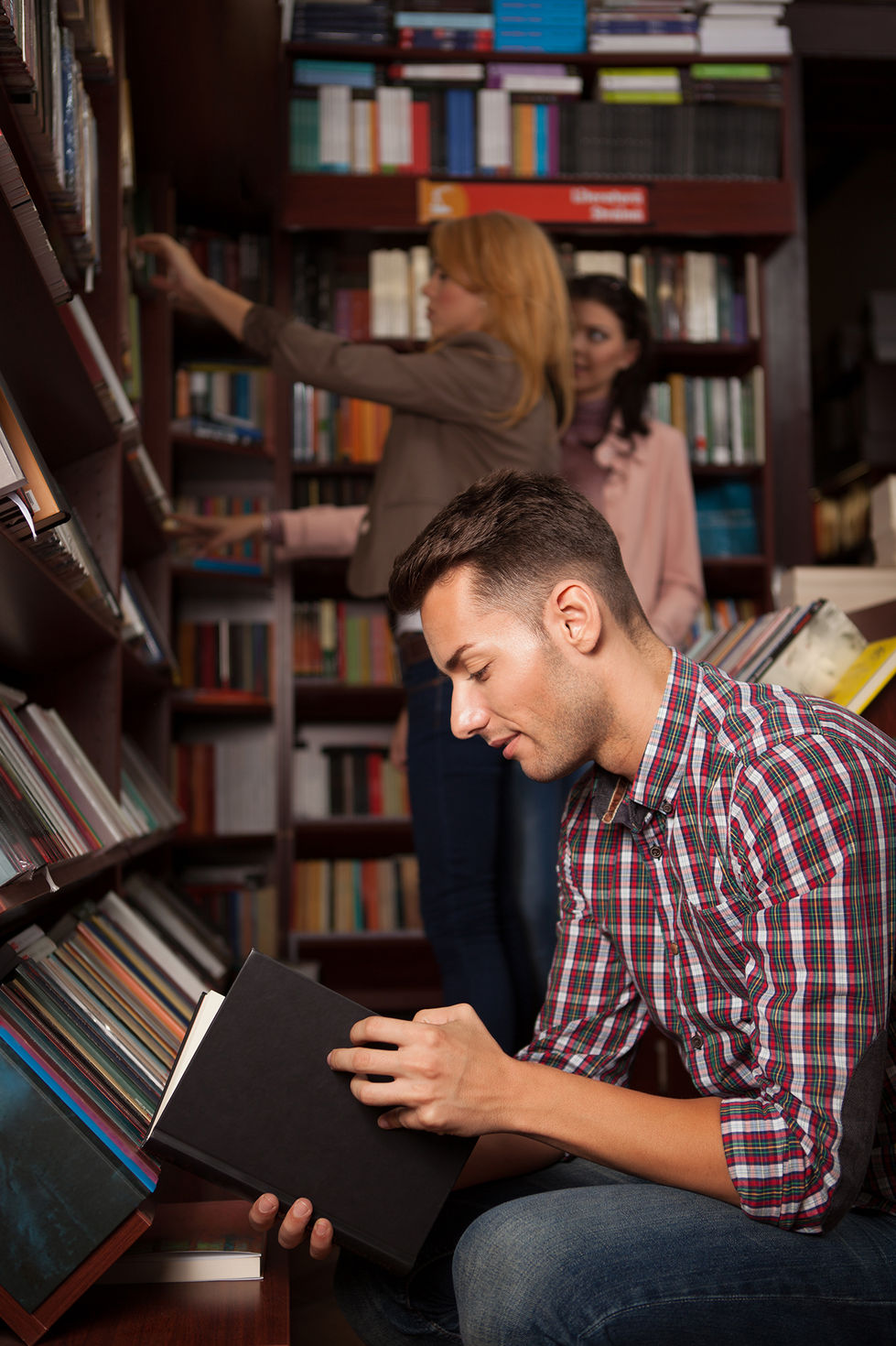 Envato image of a guy reading a book in a library.