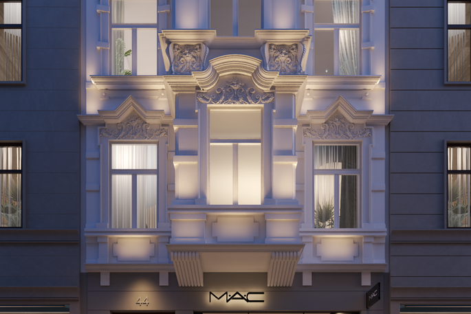 Night frontal exterior of an illuminated classical facade above a MAC storefront.