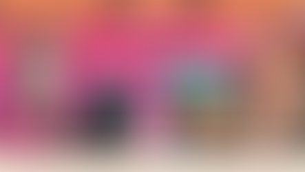 Wide podcast header with a warm pink-to-orange gradient background. Two women appear full-face left and right, smiling and wearing glasses; one wears a dark pink blouse and the other has shoulder-length light hair. Two studio microphones hang near the top corners. Foreground elements include a YA book cover featuring a dark silhouette in a cityscape and two stacked magazine covers labeled with the podcast brand. A cream footer band along the bottom displays the season and episode information and the guest/novel title.