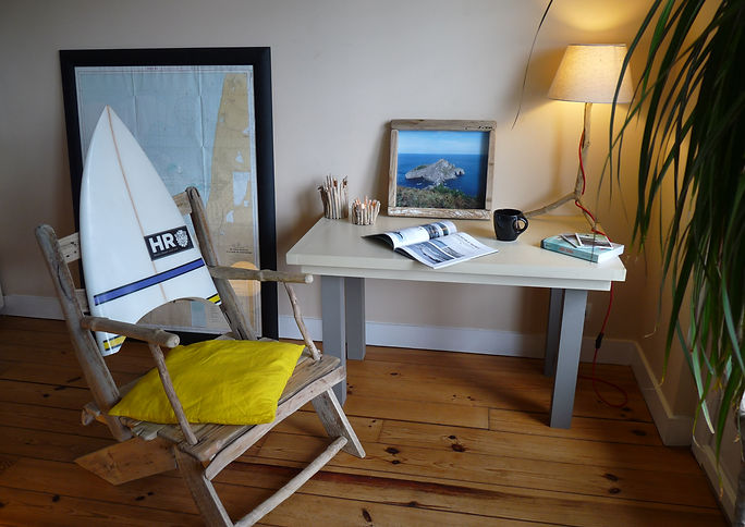 Photo d'ambiance de meubles et objets en bois flottés : fauteuil, bougeoirs, cadre, lampe.
