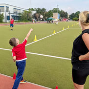 Schüler wirft Ball, Sportfest, Trainerin beobachtet
