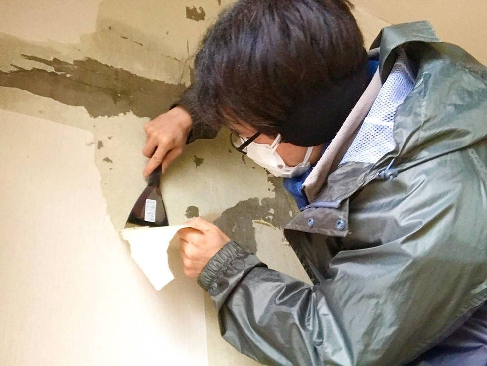 不動産投資のDIY見学会で、ヘラを使い壁紙を剥がす様子