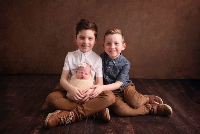 Family portrait of two boys holding their new baby sister.