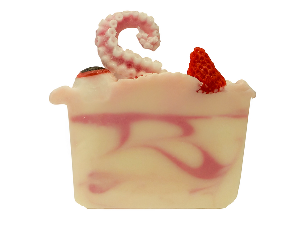 A bar of handmade soap with pink swirl base, whipped top, strawberry pieces, and curled tentacle embed on a white background