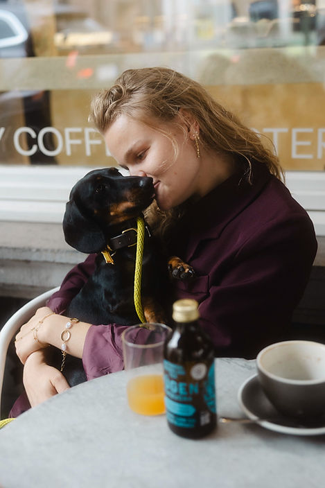 Vrouw knuffelt teckel in café