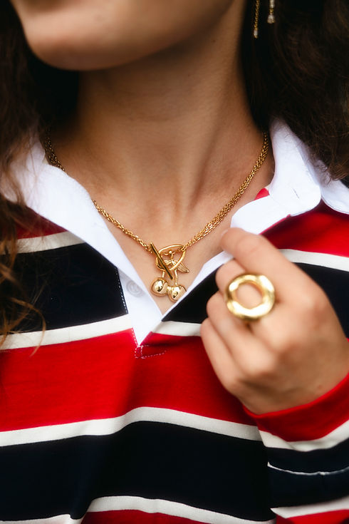 Vrouw met gouden ketting en ring, rood-wit-blauw gestreept shirt.