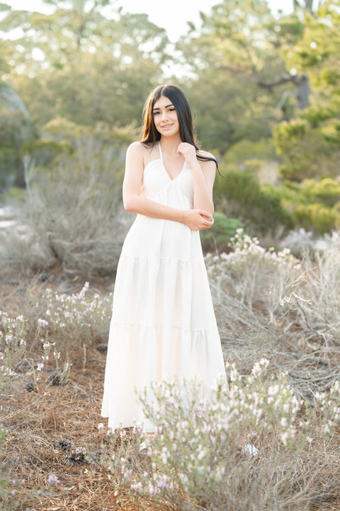 High school senior standing in a green field during a natural light Pensacola senior portrait session.