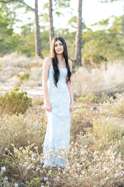 High school senior standing in a green field during a natural light Pensacola senior portrait session.