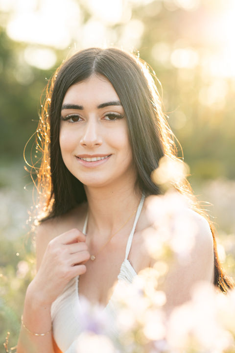 High school senior standing in a green field during a natural light Pensacola senior portrait session.