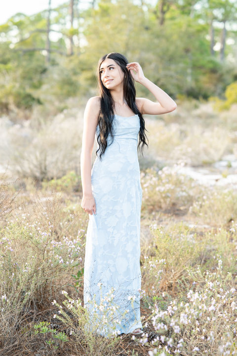 High school senior standing in a green field during a natural light Pensacola senior portrait session.