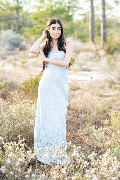 High school senior standing in a green field during a natural light Pensacola senior portrait session.
