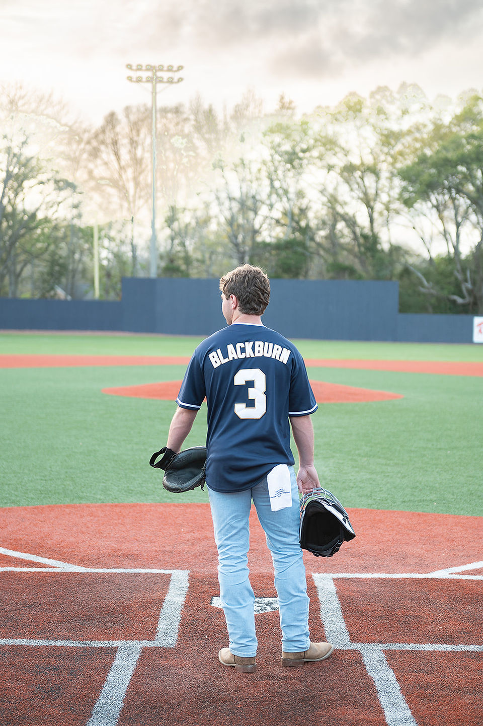 Senior boy athlete portrait featuring a baseball glove and bat as meaningful props during a professional senior portrait session