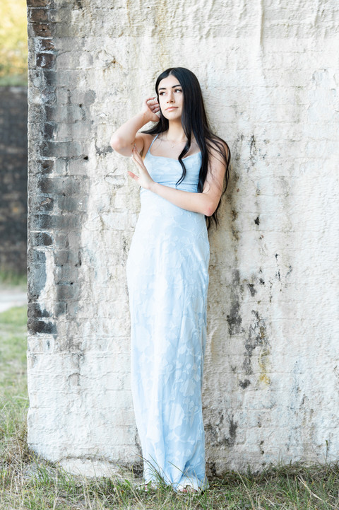 Senior girl walking under the arched corridors of the Pensacola fort during her senior portrait session.