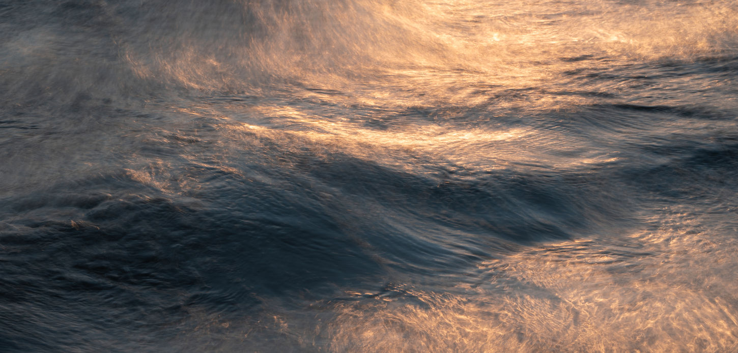 Golden sunlight reflecting on dark evening sea waves