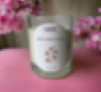 White Cherry Blossom soy wax candle on a pink satin sheet, surrounded by pretty pink flowers for a soft, floral touch.