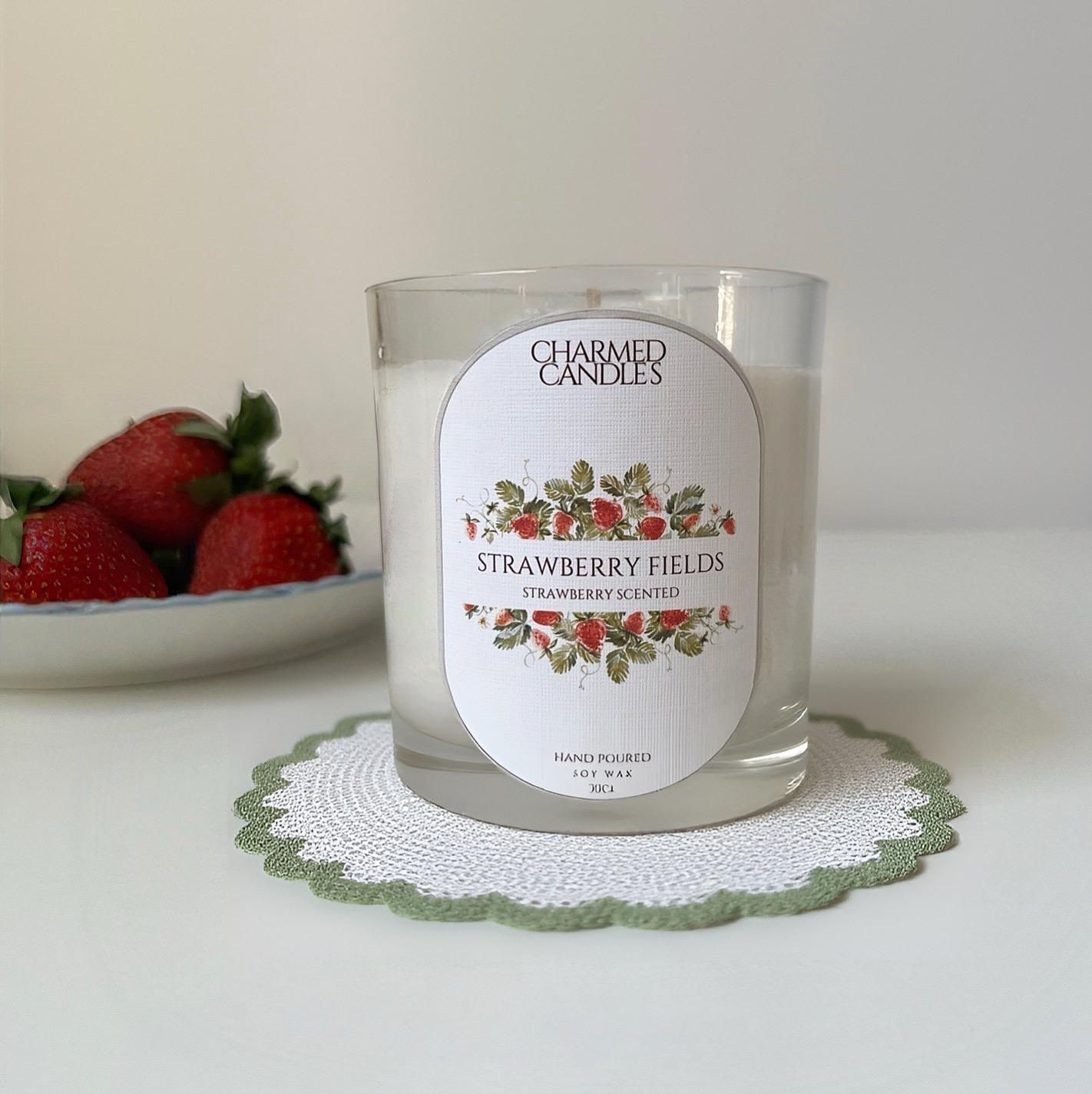 Charmed Candles Strawberry Fields soy wax candle with strawberries in background.