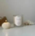 Coastal Coconut candle beside a lit seashell soy wax candle, showcasing neutral white and beige tones 