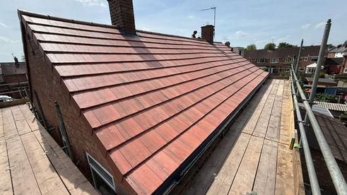 Newly slated roof installation on a brick house