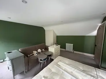 Bedroom undergoing decoration with green painted walls and ongoing furniture setup