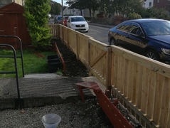 Sloped wooden fence next to a residential driveway.