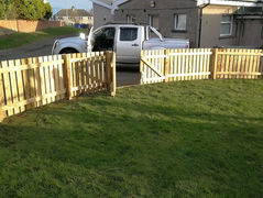 Low wooden picket fence around a front lawn.