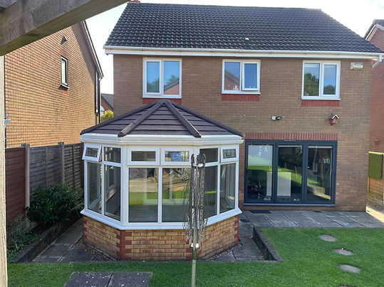 Garden view of white uPVC conservatory with dark grey tiled roof