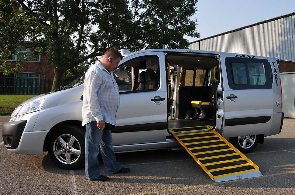 Wheelchair accessible taxi van with rear loading ramp extended to the ground