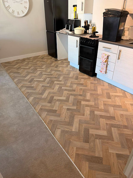 Close up of a flawless light brown herringbone parquet vinyl floor installation