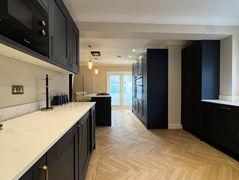 Long contemporary kitchen with white countertops and dark cabinets