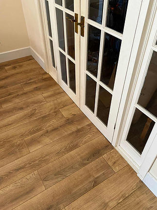 Close up of natural oak wood laminate flooring fitted next to a traditional white glazed internal door