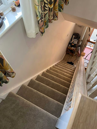High angle view looking down a straight domestic staircase fitted with a neutral grey carpet runner