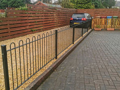 Black metal railings next to a brick driveway.