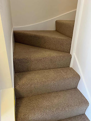 Close up of a winding domestic staircase with newly installed thick brown carpet
