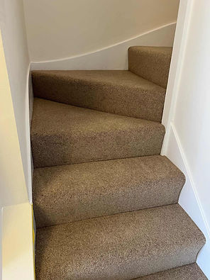 Close up of a winding domestic staircase with newly installed thick brown carpet