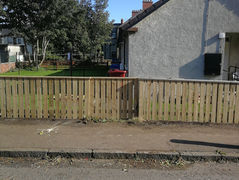 Low wooden fence bordering a front yard and pavement.