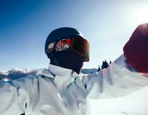 Snowboarder taking a selfie, wearing a black Mad Hatter Snow helmet and Skull and Roses snow goggles