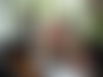 A group of colleagues interacting with each other in a boardroom, three are standing while the rest are seated around the boardroom table