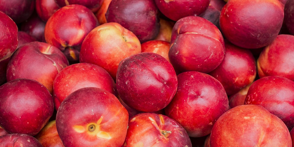 Pile of ripe, red nectarines with smooth, glossy skins. The vibrant fruits fill the entire frame, conveying a fresh and juicy feel.