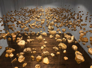 Suspended abstract installation of gold rocks hanging from a ceiling.