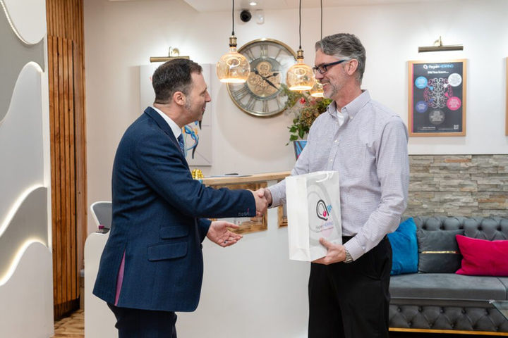 Two men shaking hands, one holding a Regain Hearing gift bag