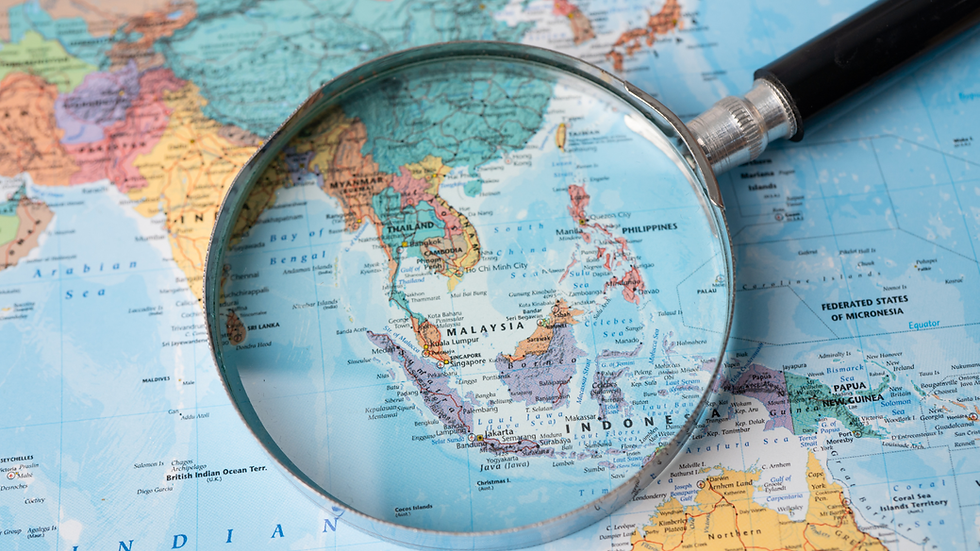 Magnifying glass over a world map, enlarging Southeast Asia and Indonesia, with country names visible.
