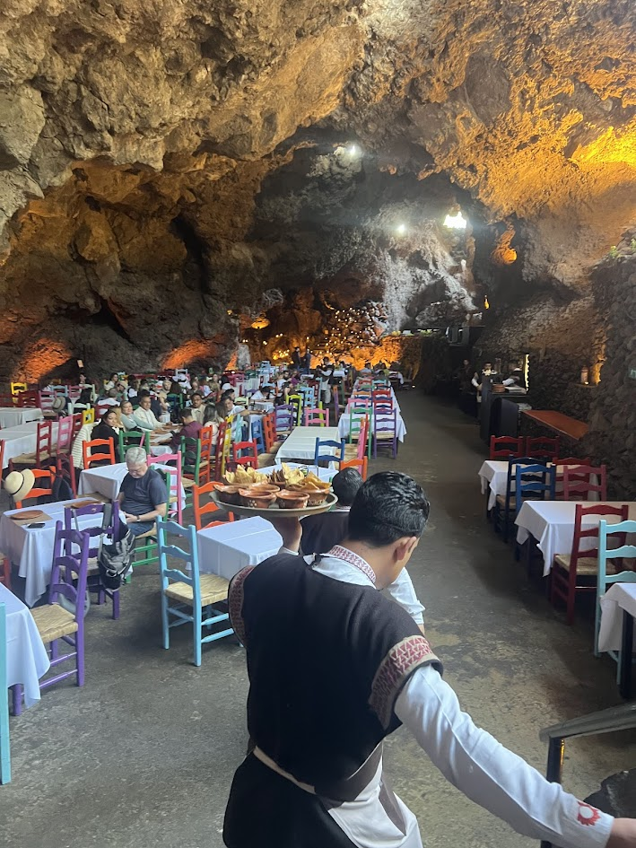 A waiter, coming down the stone staircase with chips & salsa. Note the candles burning at the rear of the grotto