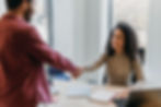Coworkers shaking hands during a workplace meeting in a bright office.