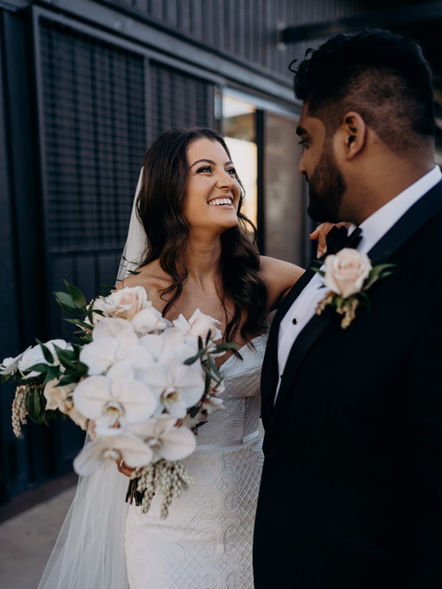 Bride and groom sharing a moment at their wedding. bride holding classic white wedding bouquet and groom in black suit with classic white buttonhole
