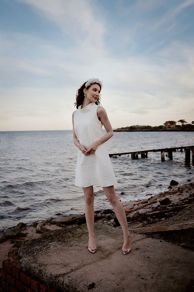a bride on the beach with a flower crown in her hair