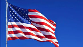 The American flag flying in the wind against a blue background