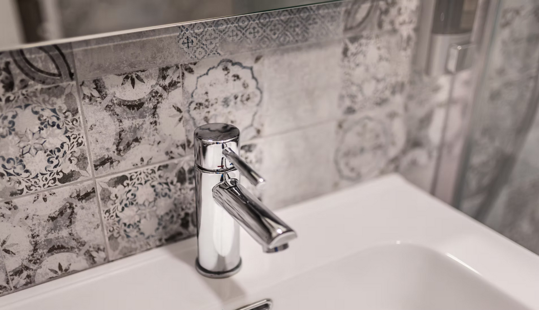 Rubinetto cromato e lavabo con piastrelle decorate