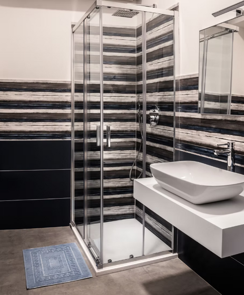 Bagno moderno con doccia in vetro, lavabo e piastrelle a strisce